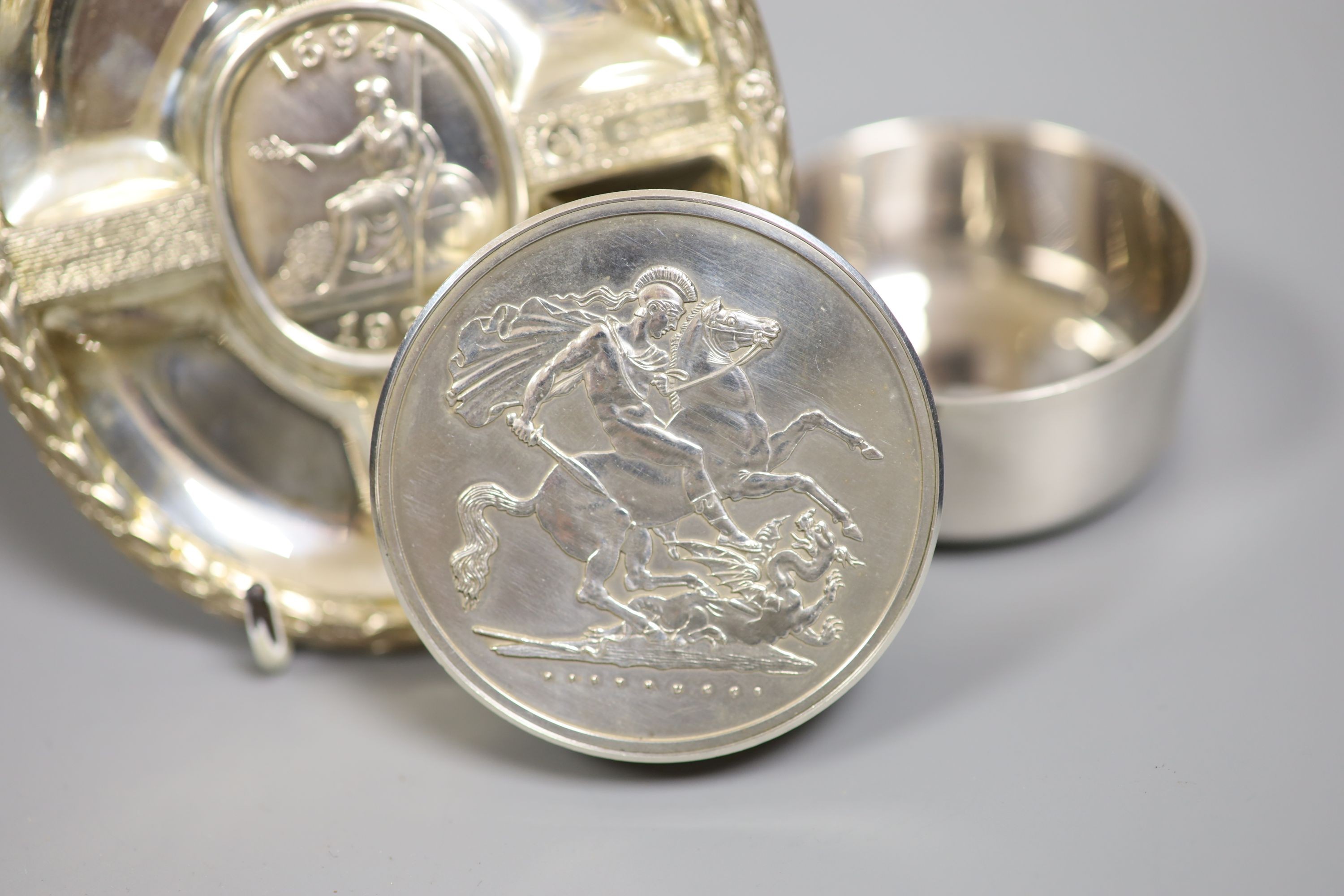 A modern silver pot and cover, decorated with St. George & The Dragon, diameter 61mm and a cased silver plaque, both by Christopher Nigel Lawrence.